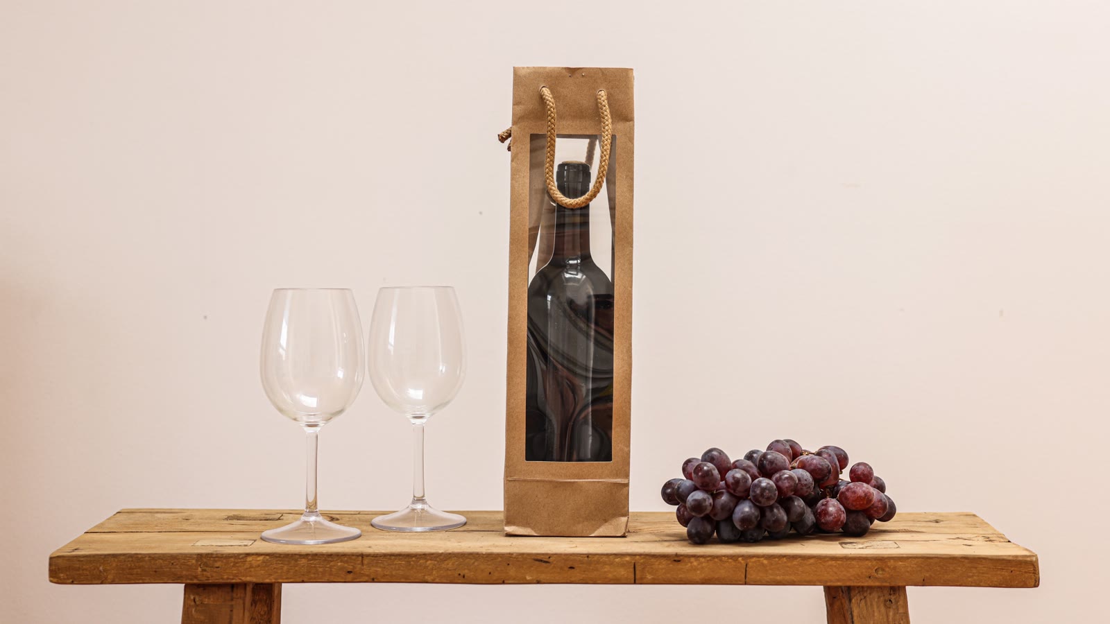 Vinflaske i gavepose med to glas og druer