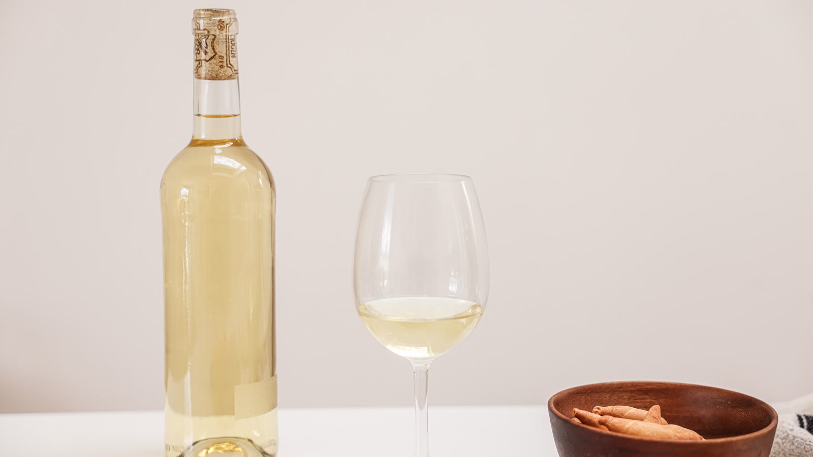 Flaske hvidvin og et glas hvidvin på et bord