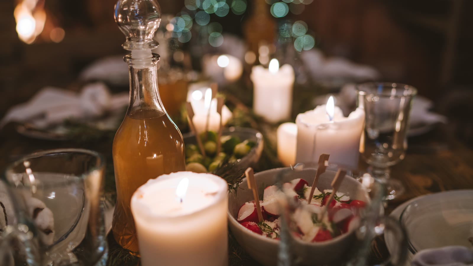 Karaffel med vin, glas og tændte stearinlys på et dækket julebord